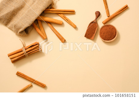 A gunny bag containing cinnamon stick decorated with cinnamon powder on minimalist background. Powder and essential oil extracted from Cinnamon (Cinnamomum) is good for health and skin 101658151