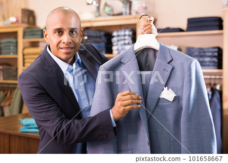 Friendly salesman offering suit in menswear boutique 101658667