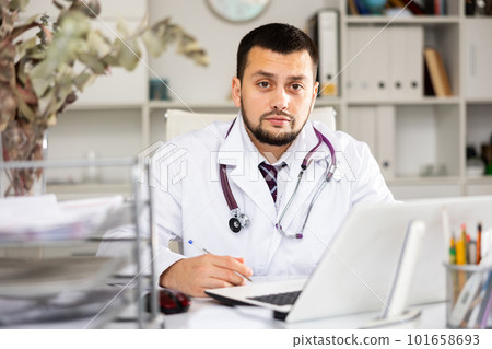 Portrait of male doctor writing in office 101658693