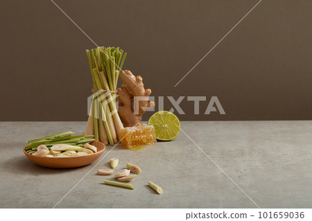 A ginger, a lemon slice and many lemongrass are displayed on minimalist background with a beeswax. Blank space to add text or promote product. Herbals can improve hair and skin condition 101659036