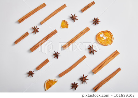 Minimal art background with cinnamon sticks, anise and dried orange slices on white background. Advertising photo for product of natural herbal extract. Top view, flat lay. 101659102