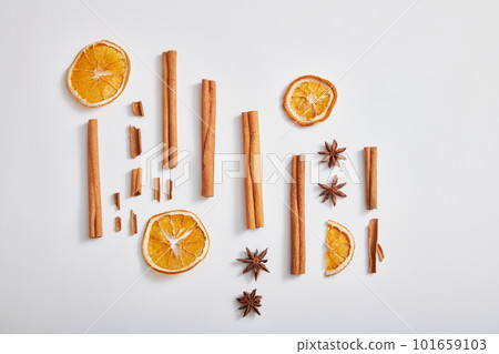 Minimal concept with cinnamon sticks, anise and dried orange slices on white background. Scene for advertising product of herbal extract. Top view, flat lay. Minimal concept with cinnamon sticks, anise and dried orange slices on white background. Scene for advertising product of herbal extract. Top view, flat lay. 101659103
