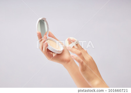 A compact powder with a makeup puff displayed on female hand model over a white background. Mockup for branding and packaging presentation A compact powder with a makeup puff displayed on female hand model over a white background. Mockup for branding and packaging presentation 101660721