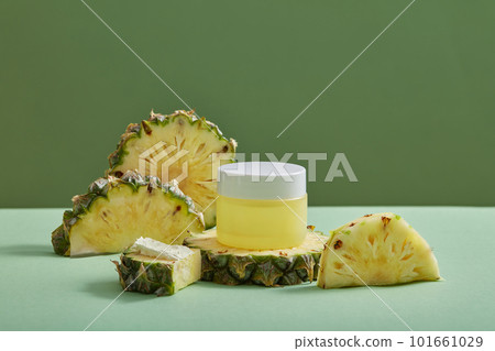 Many pineapple slices and half slices displayed with an empty label jar on minimalist background. Concept for natural, organic beauty products. 101661029