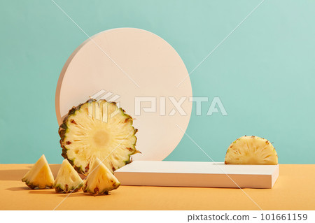 Front view of fresh pineapple slices and white empty podium on pastel blue background. Minimal art background with blank platform for display cosmetics and product of pineapple extract. 101661159