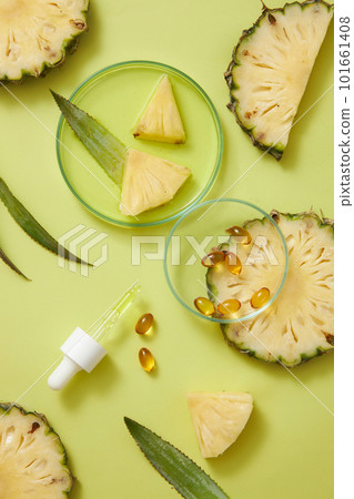 Some yellow medicines decorated with a dropper and a petri dish of essence liquid and pineapple slices. Pineapple (Ananas comosus) helps improve glowing skin and healthy hair 101661408