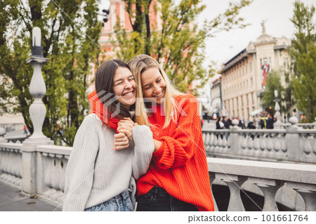 Sister hugging while walking on the city streets, having a day off to spend together  Sister hugging while walking on the city streets, having a day off to spend together  101661764