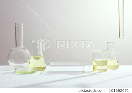 Lab theme with laboratory equipment filled yellow solution and empty transparent podium on light background. Space for product presentation Lab theme with laboratory equipment filled yellow solution and empty transparent podium on light background. Space for product presentation 101662071