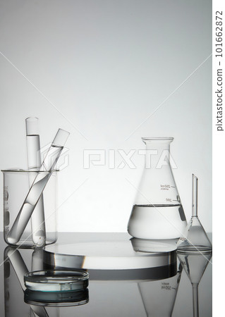 Test tubes, petri dish and erlenmeyer flask containing water, transparent podium in round shape with empty space for product presentation. Laboratory concept 101662872