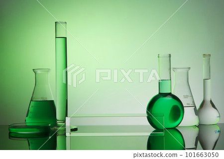 Front view of transparent empty podium, laboratory equipment - test tube, boiling flask, erlenmeyer flask and petri dish on green gradient background. Space for display product. 101663050