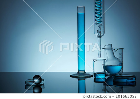 Front view of lab glassware containing blue solution in the right, on back lit background. Space for display product, text and design. Minimal concept. 101663052