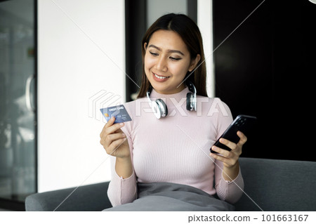 Asian girl shopping online holding credit and using smartphone enter their card number in the mobile phone app to purchase and payment in internet store Asian girl shopping online holding credit and using smartphone enter their card number in the mobile phone app to purchase and payment in internet store 101663167