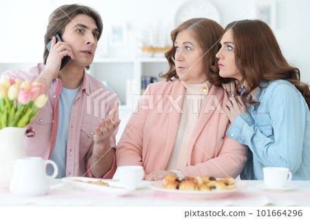 happy family of three spending time together at dinner table with cookies and tea 101664296