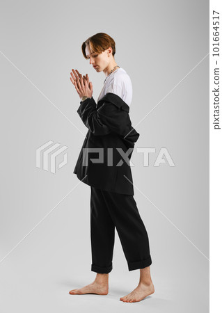 Young barefoot man in black suit posing in studio 101664517