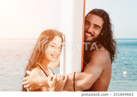 Woman man sea sup. Close up portrait of beautiful young caucasian woman with black hair and freckles looking at camera and smiling. Cute woman portrait in a pink bikini posing on sup board in the sea. 101664662