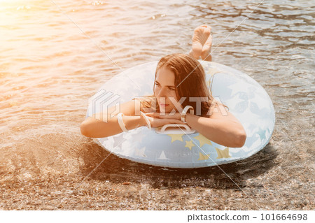 Woman summer sea. Happy woman swimming with inflatable donut on the beach in summer sunny day, surrounded by volcanic mountains. Summer vacation concept. 101664698