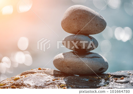 Pyramid stones on the seashore on a sunny day on the blue sea background. Happy holidays. Pebble beach, calm sea, travel destination. Concept of happy vacation on the sea, meditation, spa, calmness. Pyramid stones on the seashore on a sunny day on the blue sea background. Happy holidays. Pebble beach, calm sea, travel destination. Concept of happy vacation on the sea, meditation, spa, calmness. 101664780