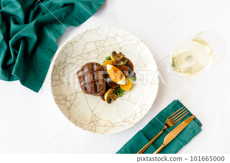 Beef steak on a white plate with a glass of wine 101665000