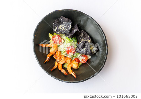 Caesar salad with shrimps on a black plate 101665002