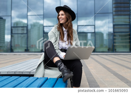 European young woman designer with a laptop in her hands on the background of street buildings 101665093