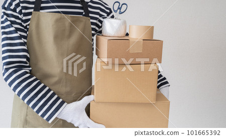 一個圍著圍裙的男人拿著紙板 | 搬家、整理和處理東西 Image 一個圍著圍裙的男人拿著紙板 | 搬家、整理和處理東西 Image 101665392
