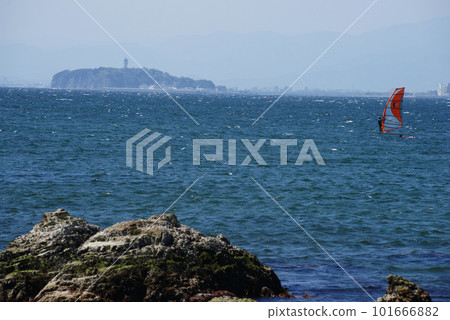 A windsurfer gliding off the coast of Morito with Enoshima in the background A windsurfer gliding off the coast of Morito with Enoshima in the background 101666882