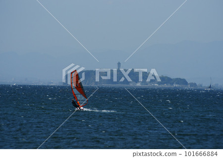 A windsurfer gliding off the coast of Morito with Enoshima in the background 101666884