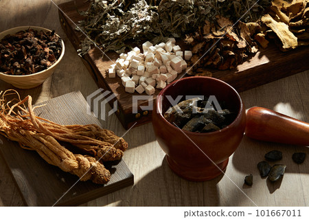 Top view of traditional herbs on wooden tray, podium, bowl, mortar and pestle on wooden table background. Herbal collection for the preparation of a tonic drink Top view of traditional herbs on wooden tray, podium, bowl, mortar and pestle on wooden table background. Herbal collection for the preparation of a tonic drink 101667011