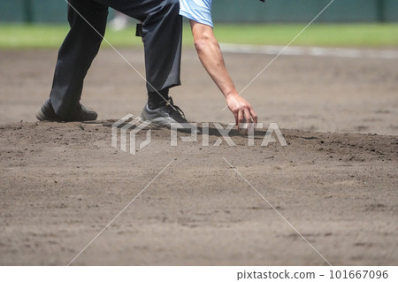 The umpire's hand cleaning the pitcher's plate on the mound during a change of offense and defense during a baseball game The umpire's hand cleaning the pitcher's plate on the mound during a change of offense and defense during a baseball game 101667096