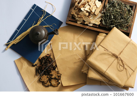Scene for advertising traditional Chinese medicine with dried herbs on wooden tray, book and medicine package on light background. Top view, copy space 101667600