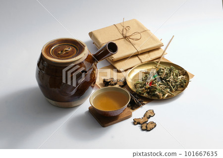 Decoction pot and medicine cup, medicine package and some dried herbs on light background. Herbal collection for the preparation of a tonic drink 101667635