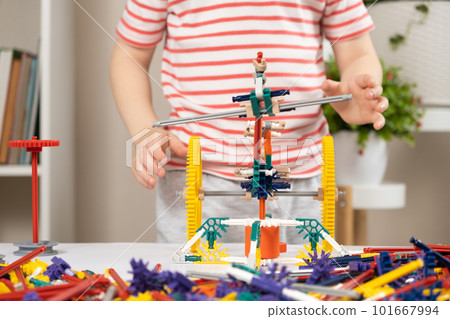 A little boy plays with a constructor, creating figures from gears and sticks. Development of logic and thinking in children 101667994