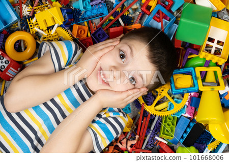 Portrait of an admiring little boy holding his head with his hands and lying among toys 101668006