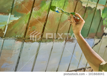 Female artist's hand with a brush painting on the wall with different colors 101668041