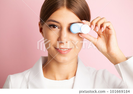 Young woman holding a white container with lenses. Young woman holding a white container with lenses. 101669184
