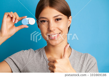 Young woman holding a white container with lenses. 101669186