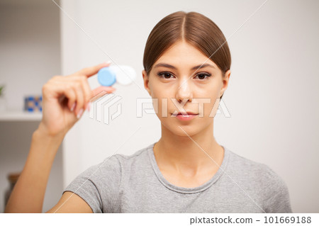 Young woman holding a white container with lenses. Young woman holding a white container with lenses. 101669188