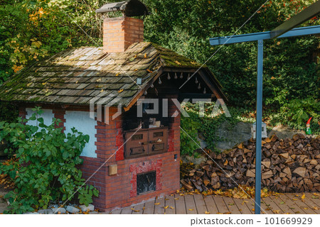 An Old Stove And Firewood For It In The Yard In The Village. Old Stone Fireplace Outdoors In The Fall. Traditional Brick Oven With Wood For Baking Bread Outdoor In Europe. An Old Stove And Firewood For It In The Yard In The Village. Old Stone Fireplace Outdoors In The Fall. Traditional Brick Oven With Wood For Baking Bread Outdoor In Europe. 101669929