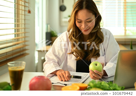 Professional nutritionist working on a diet plan, sitting with different healthy food ingredients in office. Right nutrition, healthy eating 101670442