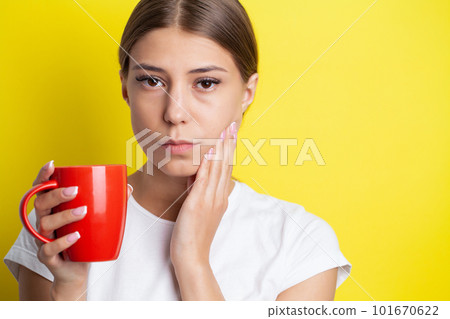 A young woman feels a toothache and holds the place of pain with her hands 101670622