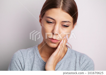 A young woman feels a toothache and holds the place of pain with her hands 101670625