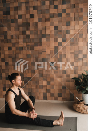A man performing gymnastic exercises on a yoga mat at home 101670749