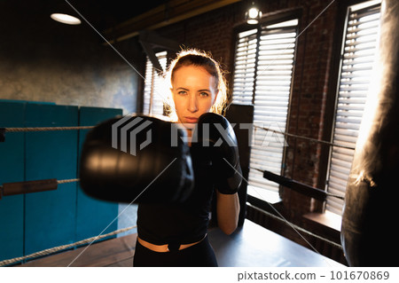 Women self defense girl power. Strong woman fighter punching with boxing gloves to camera. Healthy strong girl punching training punches looking concentrated straight. Fit body workout 101670869