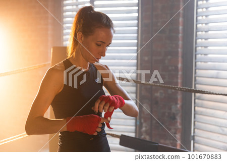 Women self defense girl power. Woman fighter preparing for fight wrapping hands with red boxing wraps sports protective bandages. Strong girl ready for fight active exercise sparring workout training 101670883