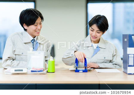 Men and women wearing work clothes punching holes Men and women wearing work clothes punching holes 101670934