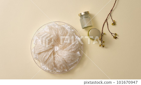 Bird nest in tray, glass water bottle without label and flower branch on light background. Mockup scene for product of swallow's nest - healthcare food, anti-aging, strengthen the immune system 101670947