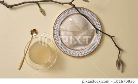 Top view of raw bird nest neatly arranged in round dishes and bowl soup, tree branch on beige background. Healthcare food, popular in Korea, China and Asia 101670956