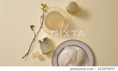 Top view of raw bird nest, bowl soup and glass bottles without label on beige background. Mockup scene for product. Healthcare food, supplements for longevity and youth. 101670957
