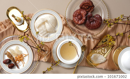 Many types of herb, lingzhi mushroom, jujube, cordyceps and ginseng displayed with edible bird nest and bird nest soup on a golden tablecloth. Combination brings many benefits for health and skin 101671002