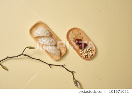 Edible bird nest placed on a wooden dish and a dish of herbal, lotus seeds, jujube (ziziphus jujuba) and rock sugar. Light background. Bird nest and herbal helps to anti-aging Edible bird nest placed on a wooden dish and a dish of herbal, lotus seeds, jujube (ziziphus jujuba) and rock sugar. Light background. Bird nest and herbal helps to anti-aging 101671021